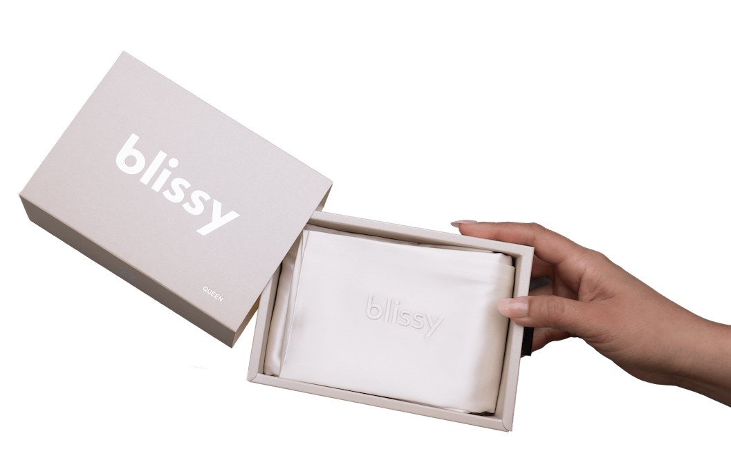 Hand holding a white Blissy pillowcase in a box